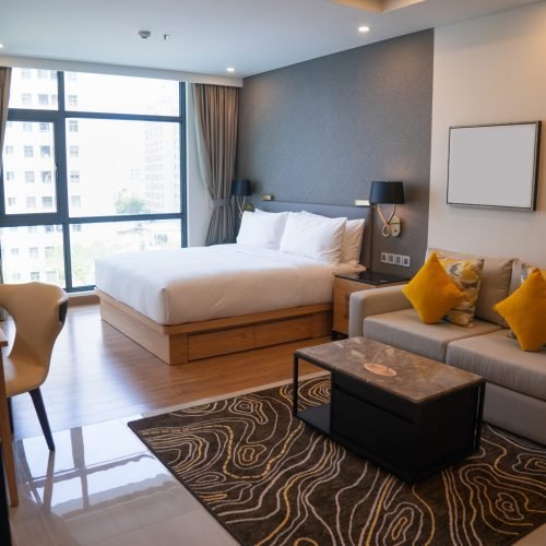 Modern studio apartment design with bedroom and living space. Hotel room panoramic window, king sized bed, couch and coffee table. City flat concept
